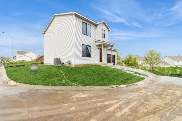 back of property featuring a lawn, central AC, and a residential view