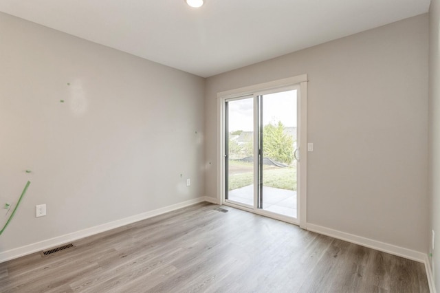 spare room with baseboards, visible vents, and light wood-style floors