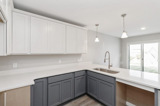 kitchen with a sink, white cabinetry, gray cabinetry, and light countertops