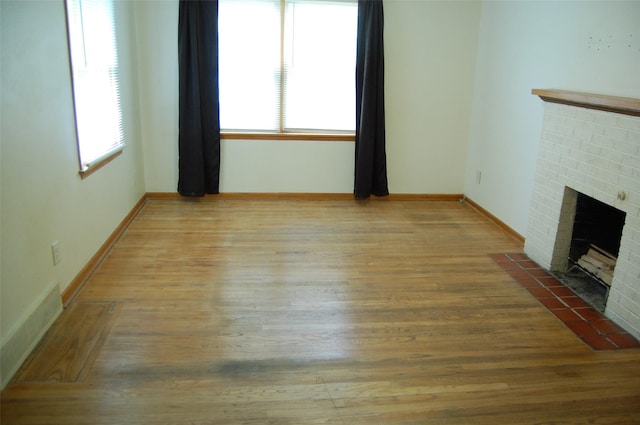 unfurnished living room featuring baseboards, wood finished floors, and a fireplace