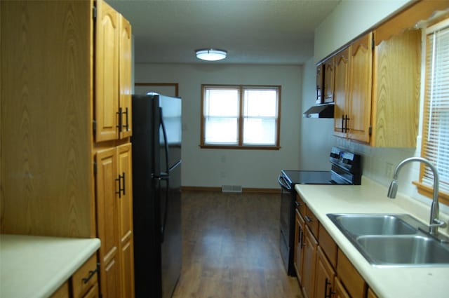 kitchen with a sink, light countertops, wood finished floors, visible vents, and black appliances