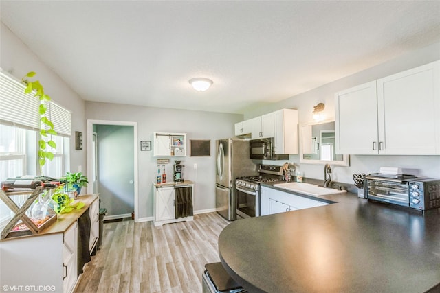 kitchen with stainless steel appliances, a sink, white cabinets, and healthy amount of natural light