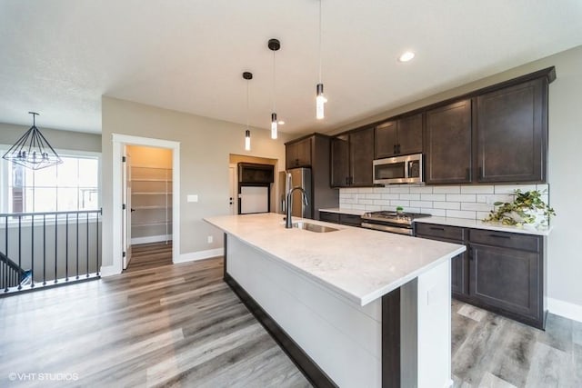 kitchen featuring stainless steel appliances, baseboards, a sink, and light wood-style flooring