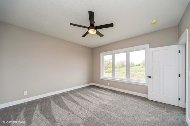 carpeted empty room with ceiling fan and baseboards