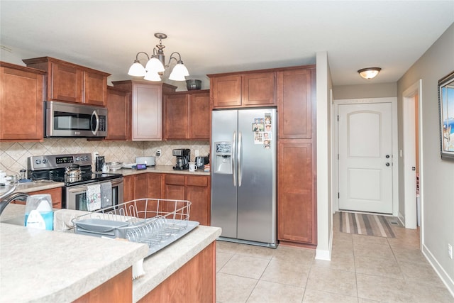 kitchen with backsplash, appliances with stainless steel finishes, brown cabinets, light countertops, and light tile patterned floors