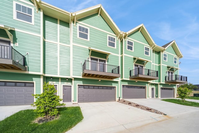 townhome / multi-family property featuring an attached garage, a balcony, and concrete driveway