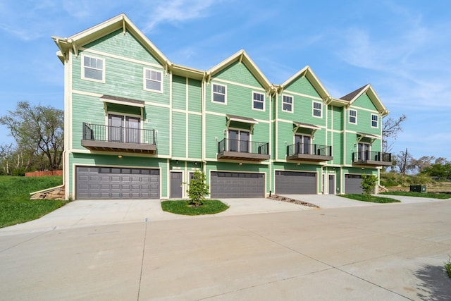 view of front facade with an attached garage, a balcony, and driveway