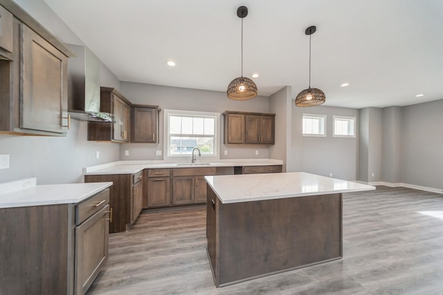 kitchen with recessed lighting, a sink, light wood finished floors, and a kitchen island