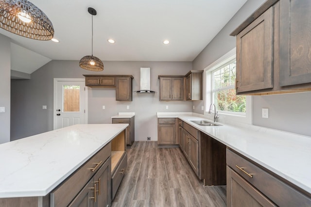 kitchen featuring pendant lighting, wall chimney exhaust hood, a sink, recessed lighting, and light wood-style flooring
