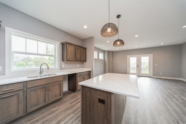 kitchen with a sink, light wood-style flooring, recessed lighting, decorative light fixtures, and a kitchen island