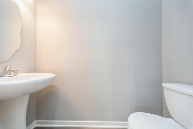 half bathroom featuring toilet and baseboards