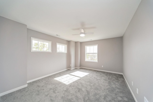 carpeted spare room featuring a ceiling fan and baseboards