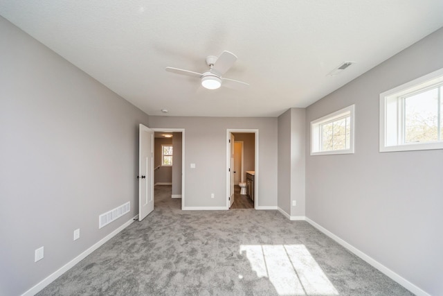 unfurnished bedroom featuring baseboards, ensuite bathroom, carpet flooring, and visible vents