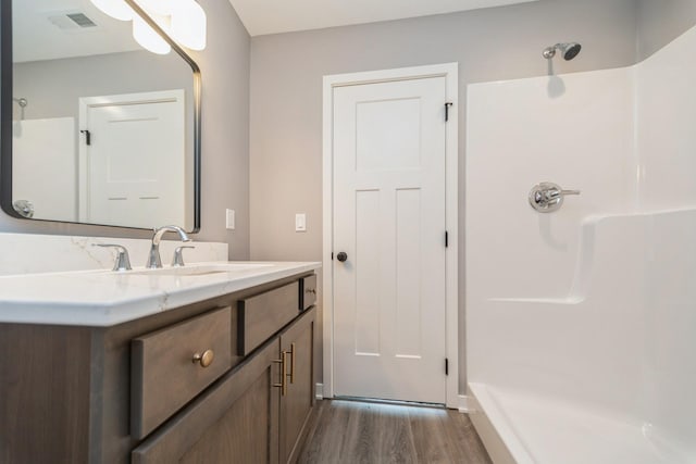 bathroom with visible vents, walk in shower, wood finished floors, and vanity