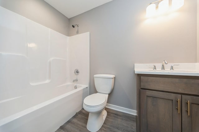 full bath featuring vanity, wood finished floors, toilet, baseboards, and shower / washtub combination