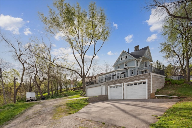 view of side of home with driveway, a chimney, and a garage