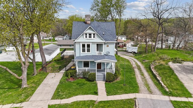 218 E Howard St, Colfax, IA 50054 - victorian home with a front lawn, roof with shingles, a chimney, a porch, and driveway