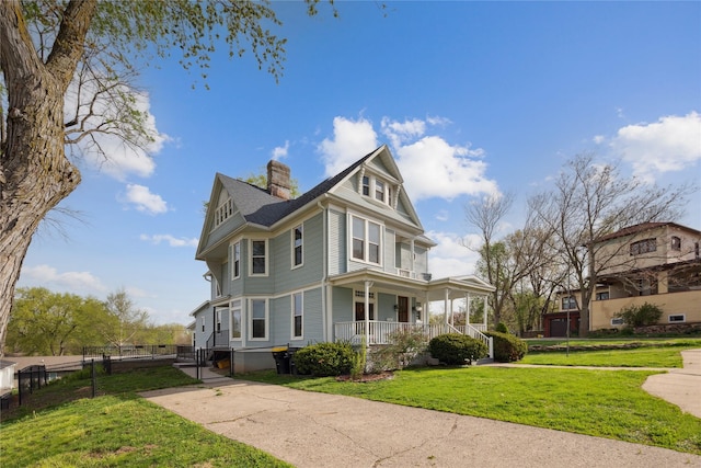 view of property exterior with a porch, a yard, fence, and a chimney