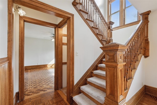 staircase featuring baseboards and ceiling fan