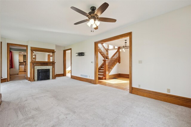 218 E Howard St, Colfax, IA 50054 - unfurnished living room with visible vents, a tile fireplace, stairway, baseboards, and light carpet