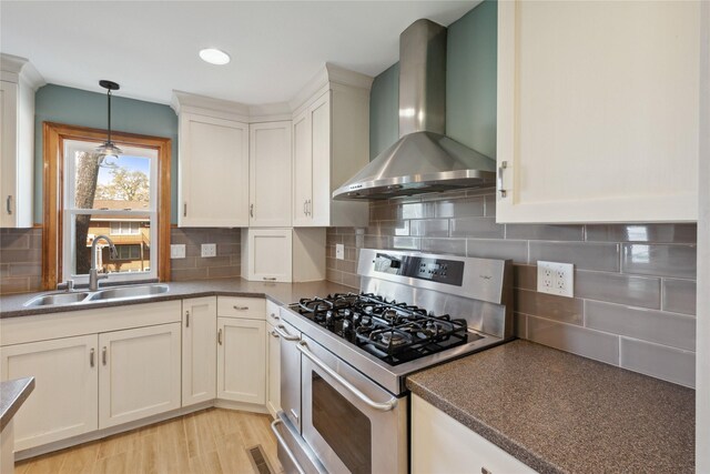 218 E Howard St, Colfax, IA 50054 - kitchen featuring wall chimney range hood, backsplash, decorative light fixtures, gas stove, and a sink