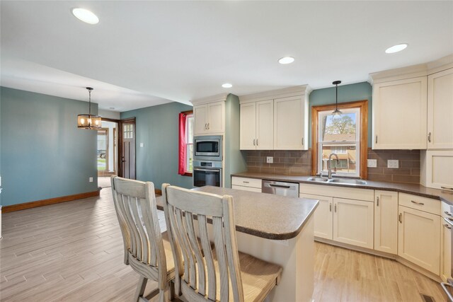 218 E Howard St, Colfax, IA 50054 - kitchen featuring a sink, light wood finished floors, stainless steel appliances, baseboards, and backsplash
