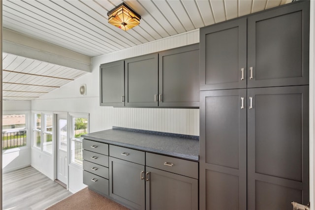 kitchen with gray cabinetry, dark countertops, wood ceiling, and light wood finished floors