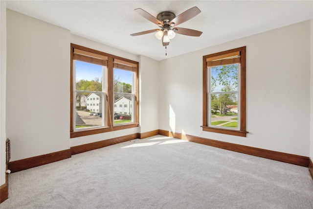 carpeted empty room featuring baseboards and ceiling fan