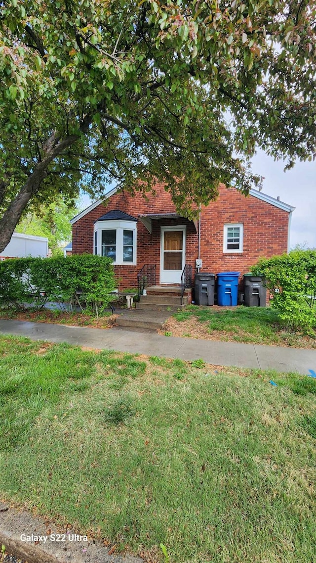 view of front facade featuring brick siding and a front yard
