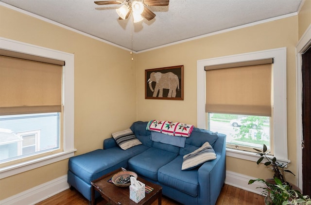 living area with crown molding, a ceiling fan, baseboards, and wood finished floors