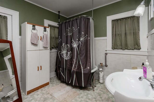 bathroom featuring crown molding, wainscoting, a sink, tile walls, and curtained shower