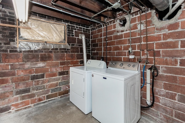laundry room with laundry area, brick wall, and washing machine and clothes dryer