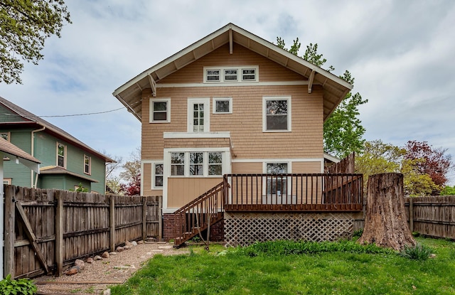 back of property with a fenced backyard, a lawn, a deck, and stairway