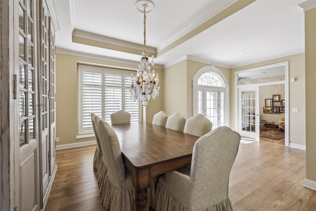 dining space featuring baseboards, french doors, wood finished floors, and a notable chandelier