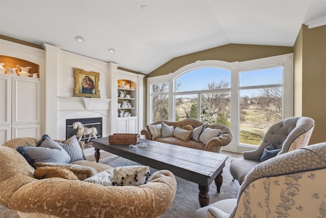 living room with crown molding, built in features, a glass covered fireplace, lofted ceiling, and recessed lighting