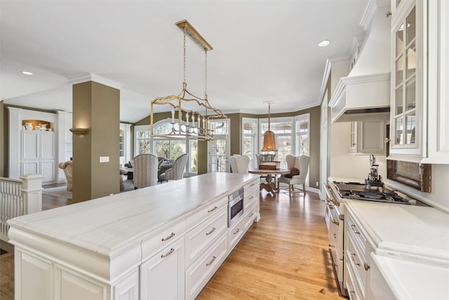 kitchen featuring premium range hood, a healthy amount of sunlight, gas range, and glass insert cabinets