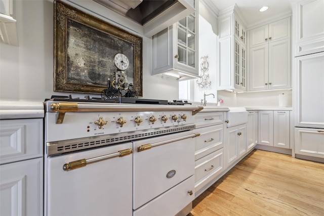 kitchen with stove, light countertops, glass insert cabinets, recessed lighting, and white cabinetry