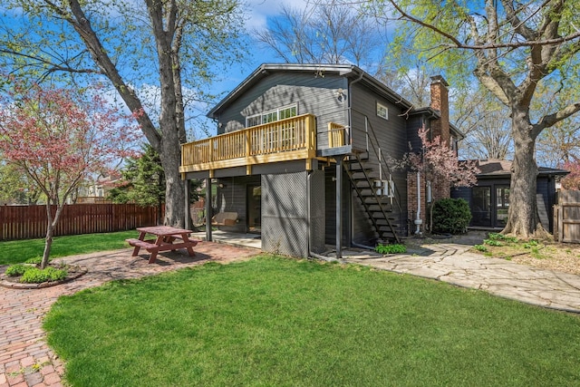 rear view of property with fence, a wooden deck, stairway, a chimney, and a yard