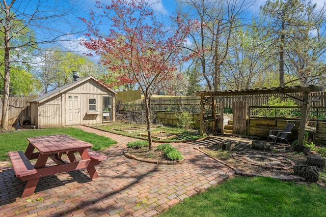 view of yard with an outdoor structure, a fire pit, a fenced backyard, and a patio area