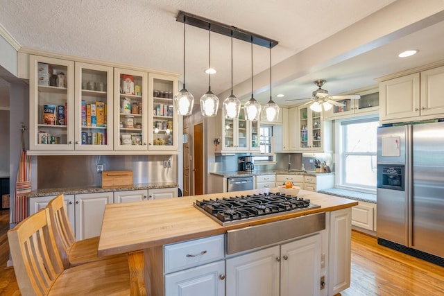 kitchen featuring appliances with stainless steel finishes, ceiling fan, a center island, and butcher block counters