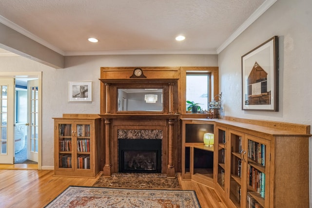 living area with a high end fireplace, ornamental molding, recessed lighting, and wood finished floors