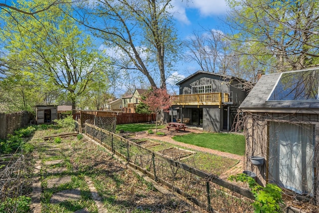 view of yard with a wooden deck, a patio, a fenced backyard, a storage shed, and an outbuilding