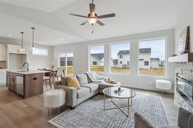 living room with a ceiling fan, lofted ceiling, wood finished floors, and a fireplace
