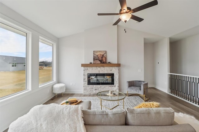 living room featuring a stone fireplace, a ceiling fan, lofted ceiling, and wood finished floors