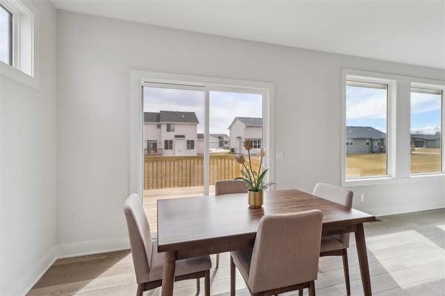 dining space with baseboards, a healthy amount of sunlight, and light wood-type flooring
