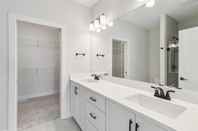 full bathroom with a sink, toilet, double vanity, and a spacious closet
