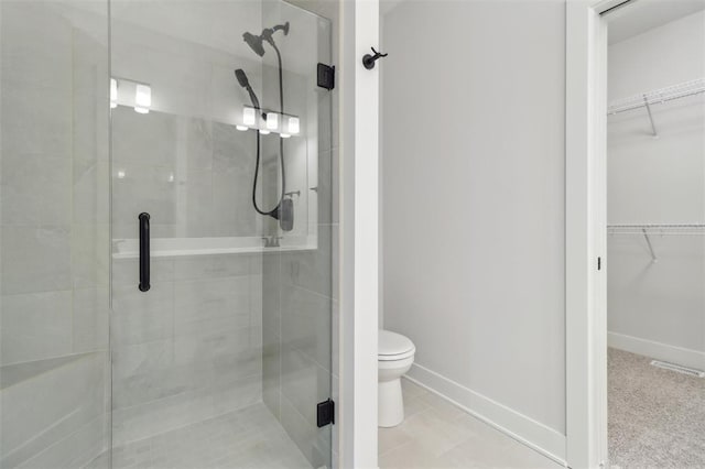 bathroom with toilet, a walk in closet, and a stall shower