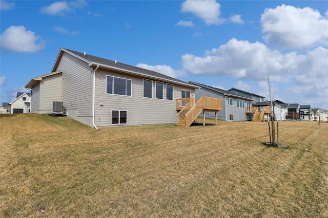 rear view of property with a lawn, a wooden deck, central air condition unit, and stairway