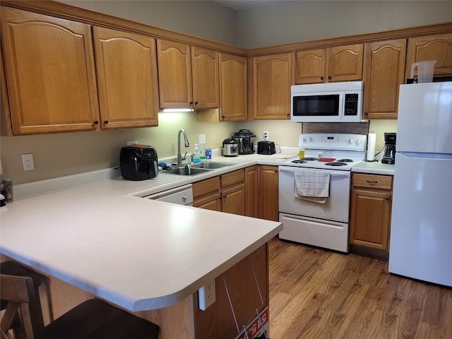 kitchen with a sink, light countertops, a peninsula, and white appliances
