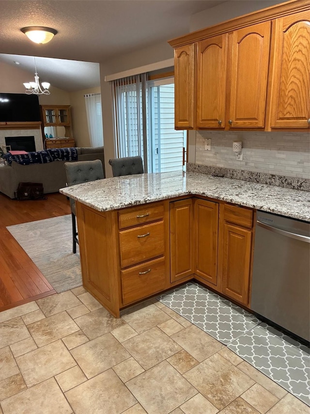 kitchen with light stone countertops, a notable chandelier, a breakfast bar area, open floor plan, and stainless steel dishwasher